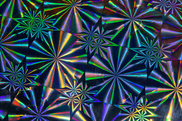 Close up photo. Vibrant holographic neon colors repeating geometric decorative pattern on a reflecting shiny surface hit by light. 90s disco  party background.