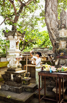 Balinese woman makes morning offerings at a hotel. Bali, Indonesia. These offerings to the spirits are made on a daily basis throughout Bali.