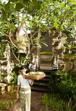 Balinese woman makes morning offerings at a hotel. Bali, Indonesia. These offerings to the spirits are made on a daily basis throughout Bali.