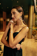Cheerful attractive woman with dark hair wearing elegant evening dress wearing stylish bright earnings. Femininity and beauty sensuality concept. 