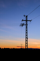 Silhouette of an electric pole on dusk background. 