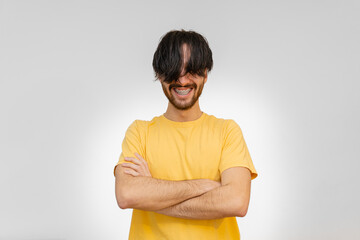 man with long hair on his face, smiling with his arms crossed needs a haircut. white background