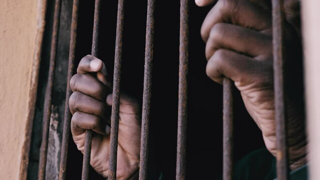 African young man behind bars staring at camera. Illegal migration,human rights