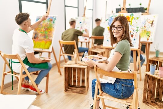 Group of people drawing at art studio. Woman smiling happy looking to the camera.