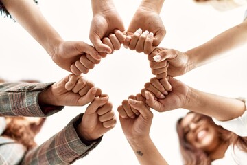 Group of young businesswoman smiling happy bump fists standing at the office.
