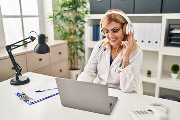 Middle age blonde woman wearing doctor uniform having medical teleconsultation at clinic