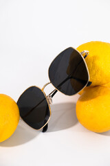 Stylish sunglasses resting on ripe juicy lemons