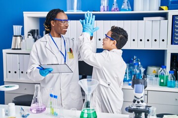 African american mother and son scientists smiling confident high five with hands raised up...