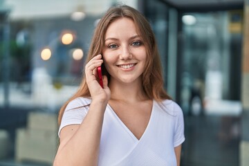 Obraz premium Young blonde woman smiling confident talking on the smartphone at street