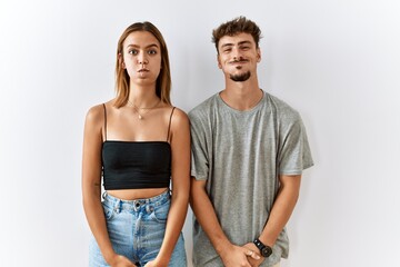 Naklejka premium Young beautiful couple standing together over isolated background puffing cheeks with funny face. mouth inflated with air, crazy expression.