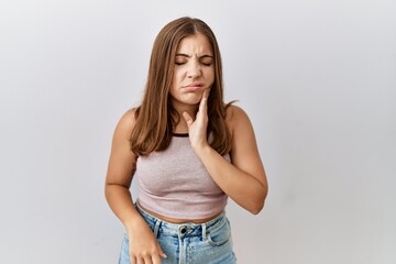 Young brunette woman standing over isolated background touching mouth with hand with painful expression because of toothache or dental illness on teeth. dentist
