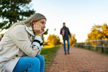 Fototapeta premium A portrait of a beautiful young girl waiting for her boyfriend sitting on a park bench.