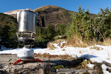 Preparing food for trips. Kettle on a gas stove. Kettle on the background of the mountains....