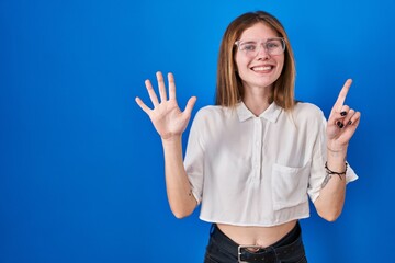 Beautiful woman standing over blue background showing and pointing up with fingers number six while smiling confident and happy.
