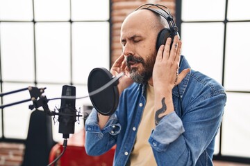 Young bald man musician singing song at music studio
