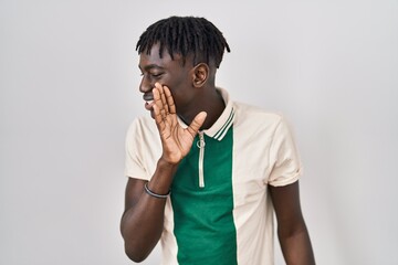 African man with dreadlocks standing over isolated background hand on mouth telling secret rumor, whispering malicious talk conversation - obrazy, fototapety, plakaty