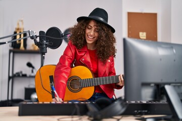 Fototapeta na wymiar Young hispanic woman musician composing song playing classical guitar at music studio