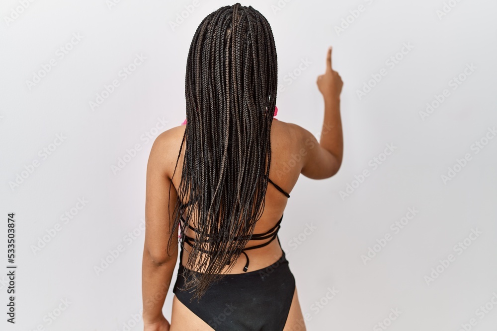 Canvas Prints Young african american woman wearing swimsuit and hawaiian lei posing backwards pointing ahead with finger hand