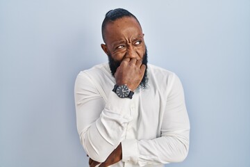 African american man standing over blue background looking stressed and nervous with hands on mouth biting nails. anxiety problem.