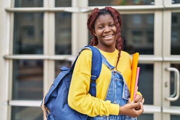 African american woman student smiling confident holding books at university