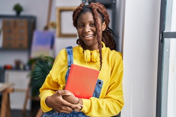 African american woman artist holding book standing at art studio