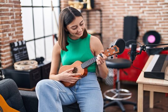Young hispanic woman musician playing ukelele at music studio