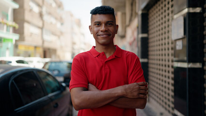 Young latin man smiling confident standing with arms crossed gesture at street