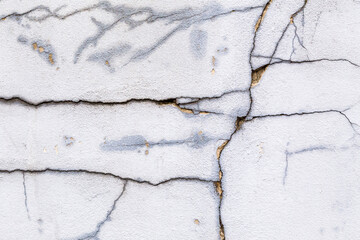 Textured grey white, concrete wall with cracks and grungy, rough painted, detail. Design element abstract background with holes, many paint patches and scratches.