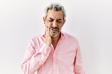 Middle age hispanic man standing over isolated background touching mouth with hand with painful expression because of toothache or dental illness on teeth. dentist