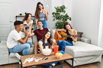 Group of young friends having party playing classical guitar at home.