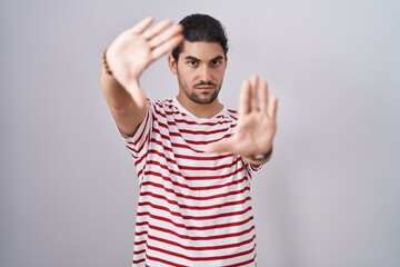 Fototapeta premium Hispanic man with long hair standing over isolated background doing frame using hands palms and fingers, camera perspective