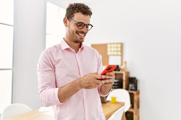 Young hispanic man smiling confident using smartphone at office
