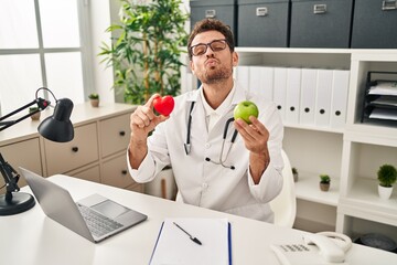 Young hispanic man working at dietitian clinic looking at the camera blowing a kiss being lovely and sexy. love expression.
