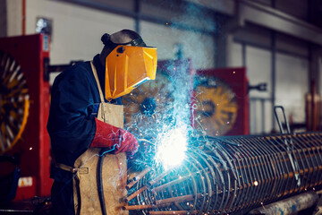 A metallurgy worker uses a welding machine for metal construction in the facility.