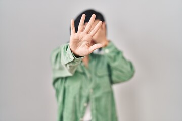 Young asian woman standing over white background covering eyes with hands and doing stop gesture with sad and fear expression. embarrassed and negative concept.