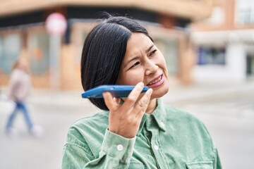 Fototapeta premium Young chinese woman talking on the smartphone at street