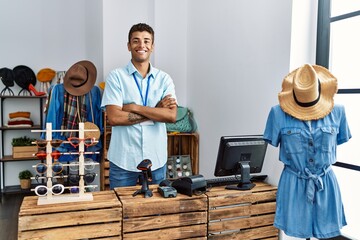 Young hispanic man working as shop assistant at retail shop