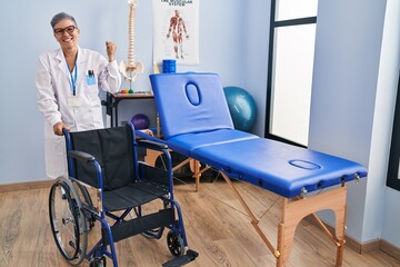 Middle age woman with wheelchair screaming proud, celebrating victory and success very excited with raised arms