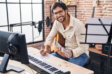 Young hispanic man musician composing song at music studio