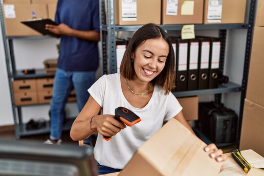 Man and woman business partners scanning package using barcode reader at storehouse