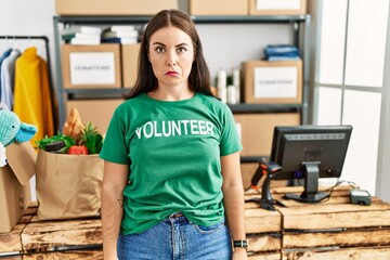 Young brunette woman wearing volunteer t shirt at donations stand depressed and worry for distress, crying angry and afraid. sad expression.