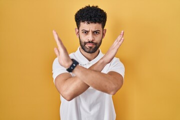 Arab man standing over yellow background rejection expression crossing arms doing negative sign, angry face