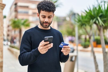 Young arab man using smartphone and credit card at street