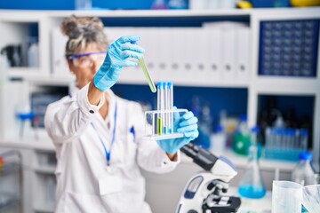 Middle age woman scientist holding test tubes at laboratory