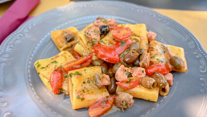 Pasta with tuna steak, olives and cherry tomatoes. Lunch served on table in restaurant. Italian cuisine. 