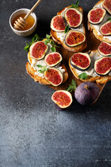 Fig bruschetta, bread and cream cheese and fruit on dark background