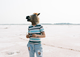 woman wearing a horse mask in a desolate landscape 