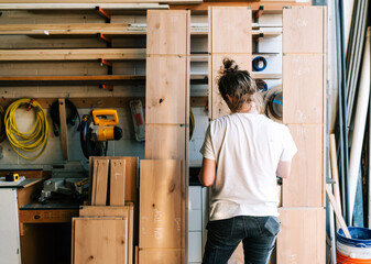 female carpenter examines some of her lumber
