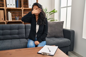 Young asian woman at consultation office covering eyes with hand, looking serious and sad. sightless, hiding and rejection concept