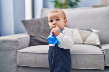 Adorable toddler drinking water standing at home